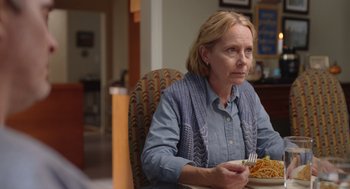 Movie still from “Beau Is Afraid” (2023), directed by Ari Aster – A woman sitting at a table with a plate of food in front of her; Close Up shot, Over the shoulder angle