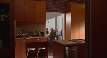 Movie still from “Beau Is Afraid” (2023), directed by Ari Aster – A group of people standing in a kitchen; Wide shot, High angle