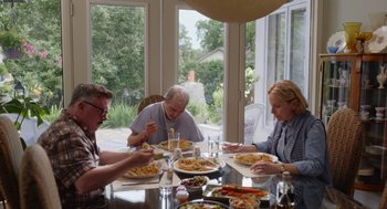 Movie still from “Beau Is Afraid” (2023), directed by Ari Aster – A group of people sitting at a dinner table; Medium shot, Over the shoulder angle