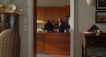 Movie still from “Beau Is Afraid” (2023), directed by Ari Aster – Two people are standing in a kitchen looking at the camera; Wide shot, Over the shoulder angle