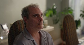 Movie still from “Beau Is Afraid” (2023), directed by Ari Aster – An older man sitting in a living room looking into the distance; Close Up shot, Low angle