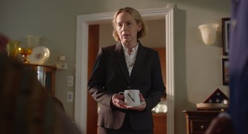 Movie still from “Beau Is Afraid” (2023), directed by Ari Aster – A woman in a suit holding a coffee mug; Medium shot, Over the shoulder angle