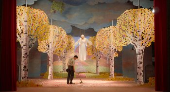 Movie still from “Beau Is Afraid” (2023), directed by Ari Aster – A man sweeping the floor in front of a painting of jesus; Wide shot, Low angle