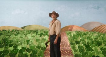 Movie still from “Beau Is Afraid” (2023), directed by Ari Aster – An old man in a hat and holding an axe in front of a brick path; Wide shot, Low angle