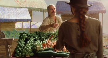 Movie still from “Beau Is Afraid” (2023), directed by Ari Aster – A man standing in front of a bunch of vegetables; Medium shot, Over the shoulder angle