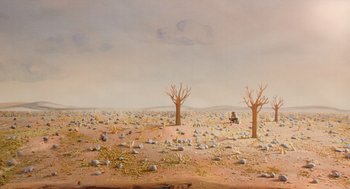 Movie still from “Beau Is Afraid” (2023), directed by Ari Aster – An oil painting of a barren landscape with trees and rocks; Extreme Wide shot, High angle