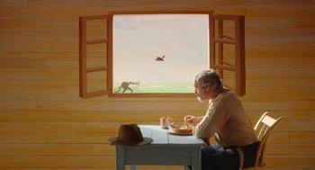 Movie still from “Beau Is Afraid” (2023), directed by Ari Aster – A man sitting at a table with a plate of food in front of an open window; Wide shot, Low angle