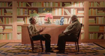 Movie still from “Beau Is Afraid” (2023), directed by Ari Aster – Two men sitting in chairs in front of bookshelves; Wide shot, Over the shoulder angle