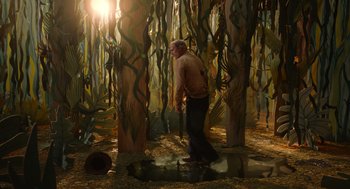 Movie still from “Beau Is Afraid” (2023), directed by Ari Aster – A man standing next to a forest filled with trees; Wide shot, High angle