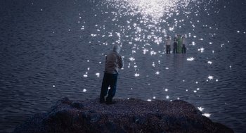 Movie still from “Beau Is Afraid” (2023), directed by Ari Aster – A man standing on the shore of a body of water; Extreme Wide shot, High angle
