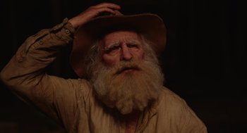 Movie still from “Beau Is Afraid” (2023), directed by Ari Aster – An old man with long white beard wearing a hat; Close Up shot, Over the shoulder angle