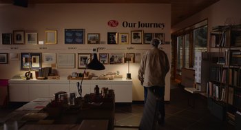 Movie still from “Beau Is Afraid” (2023), directed by Ari Aster – A man standing in front of a wall with many pictures on it; Wide shot, Low angle
