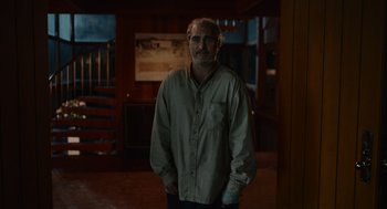 Movie still from “Beau Is Afraid” (2023), directed by Ari Aster – A man standing in a room with his hands in his pockets; Medium shot, Low angle