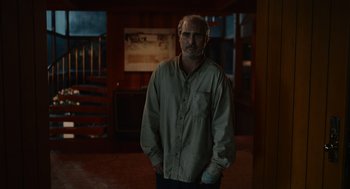 Movie still from “Beau Is Afraid” (2023), directed by Ari Aster – A man standing in a room with his hands in his pockets; Medium shot, High angle