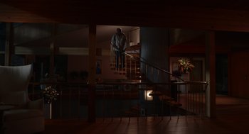 Movie still from “Beau Is Afraid” (2023), directed by Ari Aster – A man standing on the bottom of a staircase; Extreme Wide shot, Low angle
