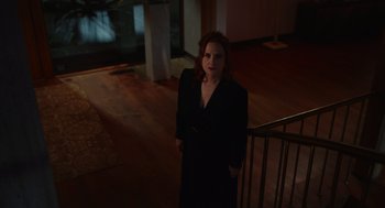 Movie still from “Beau Is Afraid” (2023), directed by Ari Aster – A woman in a black coat standing on a staircase; Wide shot, High angle
