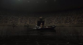 Movie still from “Beau Is Afraid” (2023), directed by Ari Aster – A man is in a boat in the middle of the water; Extreme Wide shot, High angle