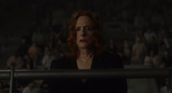 Movie still from “Beau Is Afraid” (2023), directed by Ari Aster – A woman with red curly hair standing in front of a crowd; Close Up shot, High angle