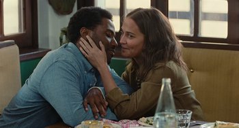 A man and a woman sitting at a dinner table kissing