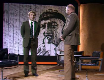 Movie still from “Becoming Cousteau” (2021), directed by Liz Garbus – Two men in suits stand in front of a painting; Wide shot, Low angle