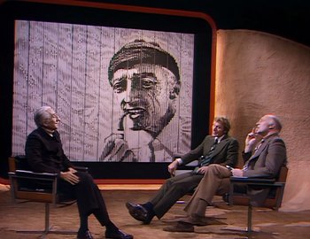 Movie still from “Becoming Cousteau” (2021), directed by Liz Garbus – A group of people sitting in front of a painting; Wide shot, Over the shoulder angle