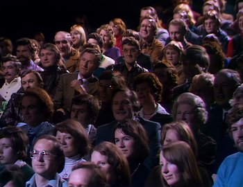 Movie still from “Becoming Cousteau” (2021), directed by Liz Garbus – A large group of people sitting in a room; Wide shot, High angle