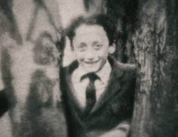 Movie still from “Becoming Cousteau” (2021), directed by Liz Garbus – An old photo of a man in a suit; Extreme Close Up shot, High angle