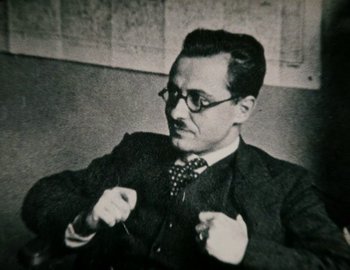 Movie still from “Becoming Cousteau” (2021), directed by Liz Garbus – An old black and white photo of a man wearing a suit and tie; Close Up shot, Low angle