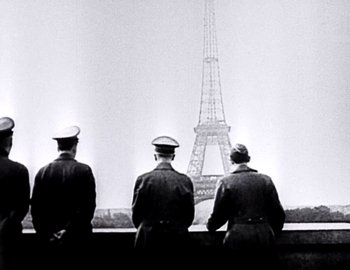 Movie still from “Becoming Cousteau” (2021), directed by Liz Garbus – A group of men standing next to each other in front of the eiffel tower; Wide shot, Low angle