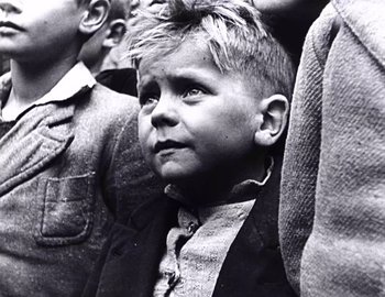 Movie still from “Becoming Cousteau” (2021), directed by Liz Garbus – An old photo of a young boy in a crowd; Close Up shot, High angle
