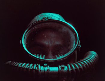 Movie still from “Becoming Cousteau” (2021), directed by Liz Garbus – A person wearing a gas mask in the dark; Close Up shot, Overhead angle