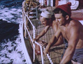 Movie still from “Becoming Cousteau” (2021), directed by Liz Garbus – A man and a woman on a boat in the ocean; Medium shot, High angle