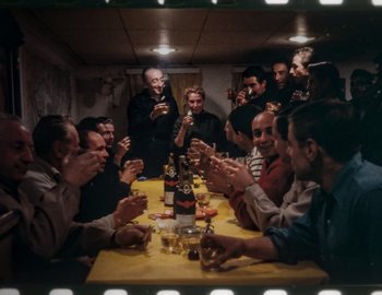 Movie still from “Becoming Cousteau” (2021), directed by Liz Garbus – A group of people sitting at a table with drinks; Wide shot, High angle