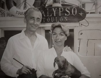 Movie still from “Becoming Cousteau” (2021), directed by Liz Garbus – An old photo of a man and a woman holding a dog; Close Up shot, Low angle