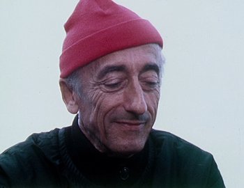 Movie still from “Becoming Cousteau” (2021), directed by Liz Garbus – An older man wearing a red hat and a black jacket; Close Up shot, Low angle