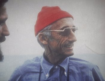 Movie still from “Becoming Cousteau” (2021), directed by Liz Garbus – An older man wearing a red hat and glasses; Close Up shot, Low angle