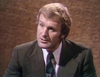 Movie still from “Becoming Cousteau” (2021), directed by Liz Garbus – A person wearing a suit and tie; Close Up shot, Low angle