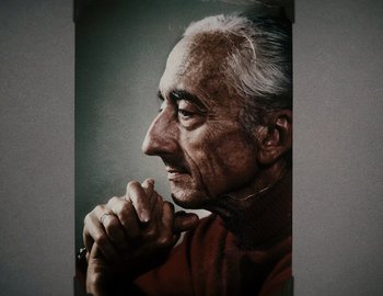 Movie still from “Becoming Cousteau” (2021), directed by Liz Garbus – An old man with a gray beard is holding his hands to his face; Extreme Close Up shot, Low angle