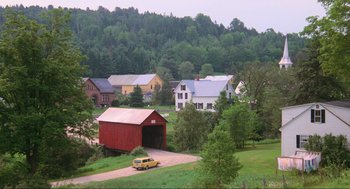 Movie still from “Beetlejuice” (1988), directed by Tim Burton – A yellow van parked in front of a red covered bridge; Extreme Wide shot, High angle