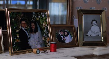 Movie still from “Beetlejuice” (1988), directed by Tim Burton – A table topped with pictures of a bride and groom; Close Up shot, Over the shoulder angle