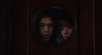 Movie still from “Beetlejuice” (1988), directed by Tim Burton – A man and a woman looking through a round window; Close Up shot, Low angle