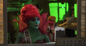 Movie still from “Beetlejuice” (1988), directed by Tim Burton – A woman dressed as a fairy sits at a desk; Medium shot, Over the shoulder angle