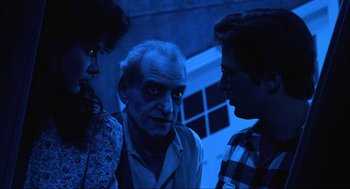 Movie still from “Beetlejuice” (1988), directed by Tim Burton – A man and two women standing next to each other in front of a building; Medium shot, Over the shoulder angle