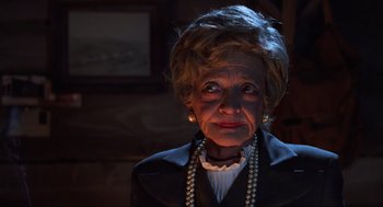 Movie still from “Beetlejuice” (1988), directed by Tim Burton – An older woman wearing pearls and a black jacket; Close Up shot, Low angle