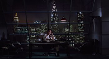 Movie still from “Beetlejuice” (1988), directed by Tim Burton – A man sitting at a desk in front of a large window; Wide shot, High angle