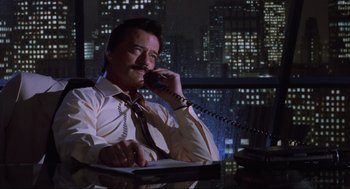 Movie still from “Beetlejuice” (1988), directed by Tim Burton – A man sitting at a desk talking on a phone; Medium shot, Low angle