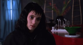 Movie still from “Beetlejuice” (1988), directed by Tim Burton – A woman with long black hair sitting in a dark room; Close Up shot, Low angle