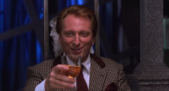 Movie still from “Beetlejuice” (1988), directed by Tim Burton – A man holding a wine glass in his right hand; Close Up shot, Low angle