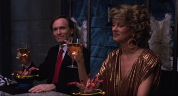 Movie still from “Beetlejuice” (1988), directed by Tim Burton – A man and a woman sitting at a table with a glass of wine; Medium shot, Low angle