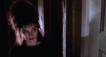 Movie still from “Beetlejuice” (1988), directed by Tim Burton – A woman in a black shirt is looking at the camera; Close Up shot, Low angle